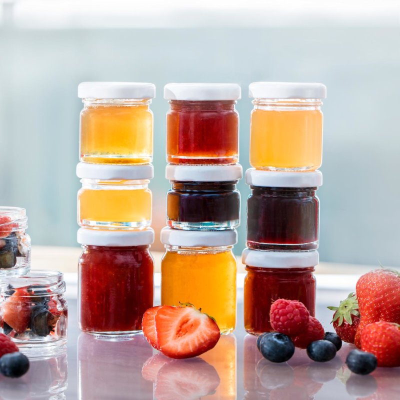 Small glass preserve jars with fruit in a bright natural setting