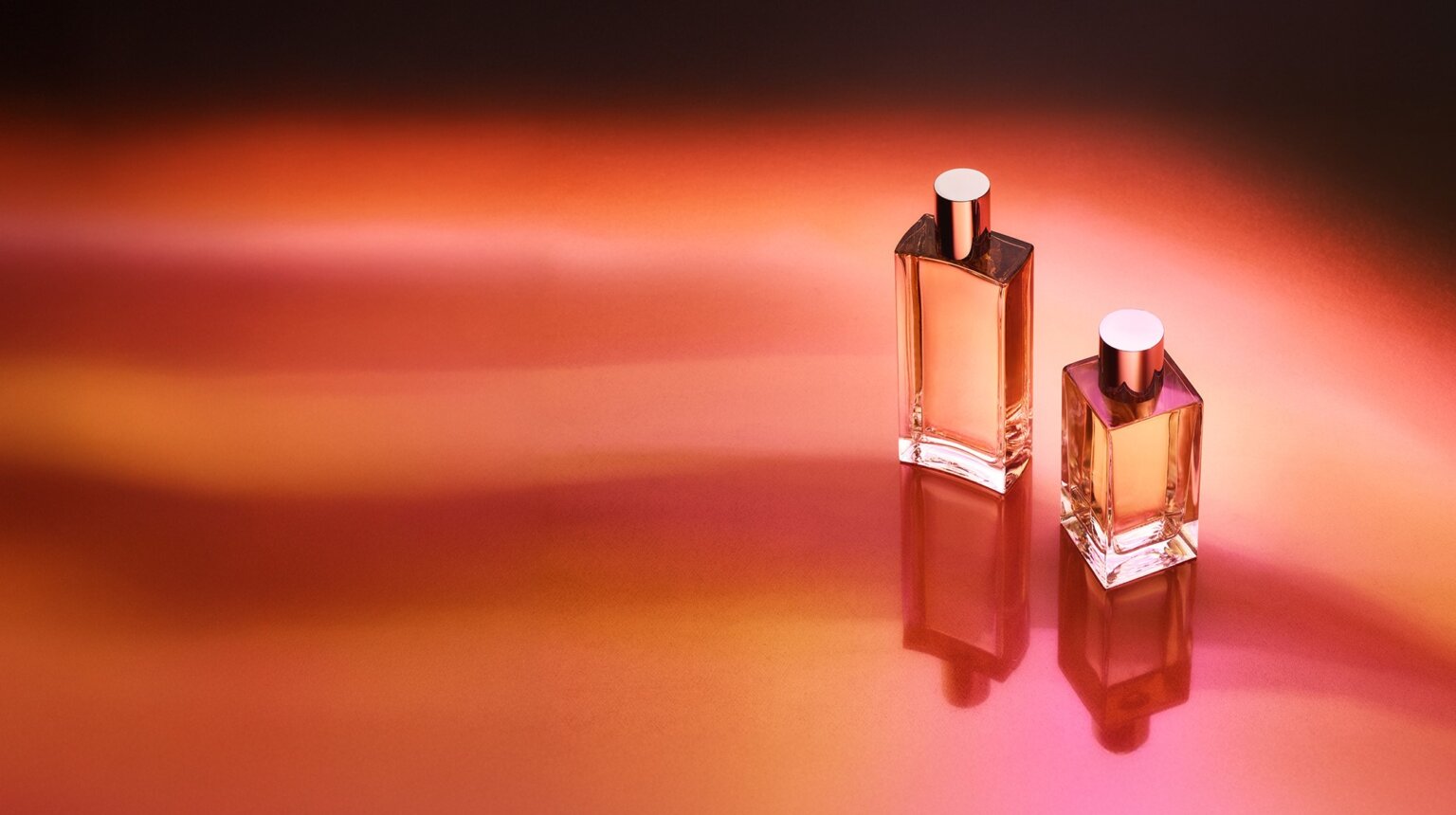 Premium glass perfume bottles in warm amber and rose light