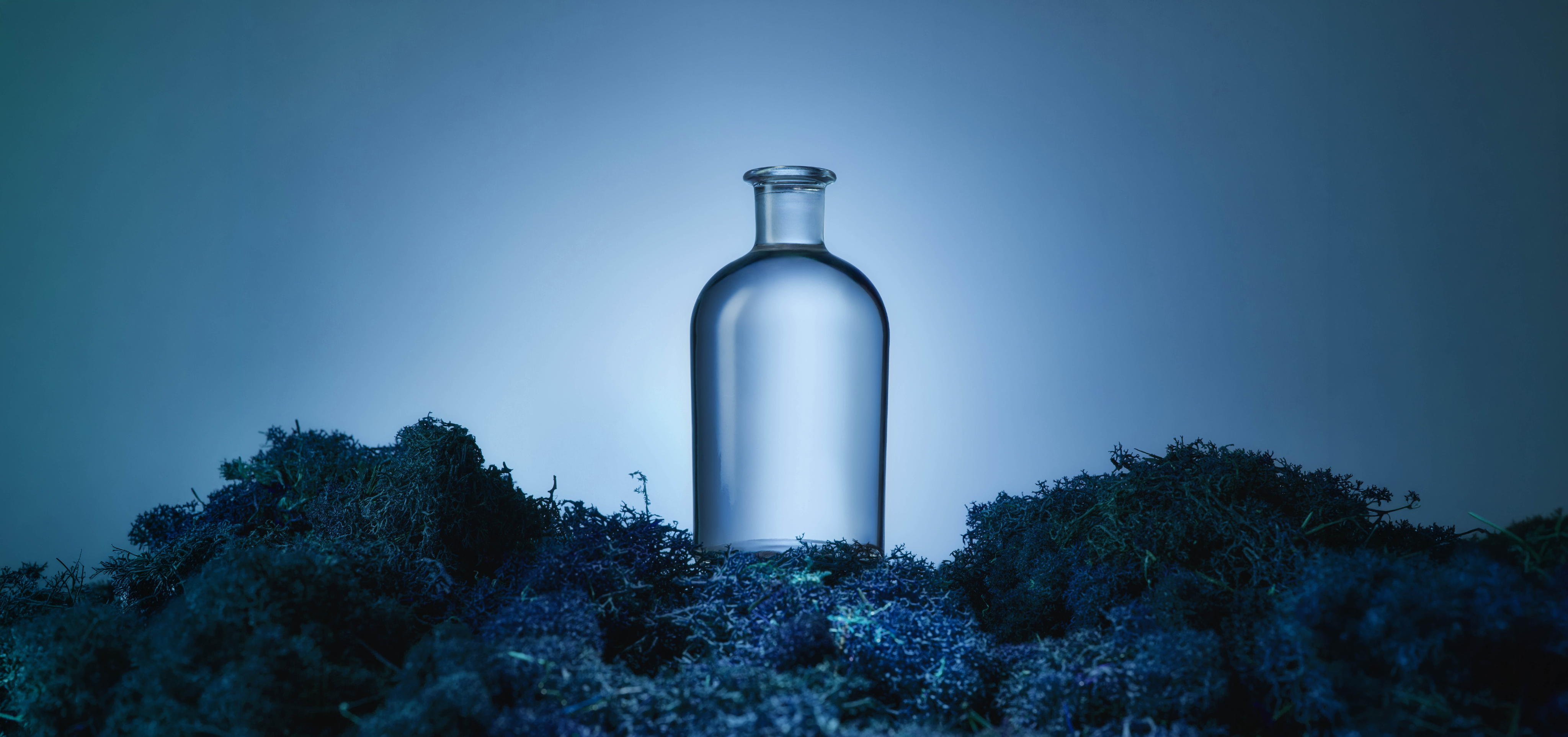Clear blue glass bottle on a textured blue surface